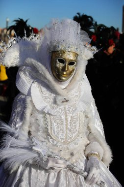 Venice, VE, Italy - February 13, 2024: person with an ancient golden mask and embroidered white dress at the Venetian carnival clipart