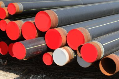 Gaz ağı altyapı inşaatı için bir yol inşaatında büyük metal boruların depolanması