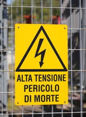 Sign in the fence of the power station with the large text in Italian meaning High Voltage Danger of Death to avoid the risk of electrocution to people clipart