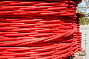 Büyük kırmızı makaralı yüksek voltajlı elektrik kablosu elektrik santralinden elektrik taşımak için kullanılır.