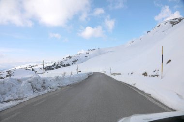 icy slippery mountain road with snow on the sides and posts to mark the limit of the roadway seen from inside a car clipart