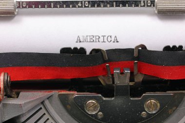 Typewritten AMERICA text in black ink on white paper with a typewriter clipart