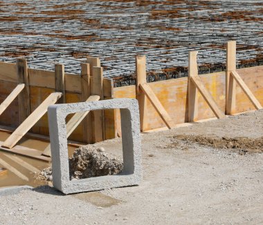 İnşaat alanındaki binanın temelini insanlar olmadan atmak için çimento döşeme sırasında sarı ahşap kalaslarla yapılmış kare beton ve biçimlendirme.