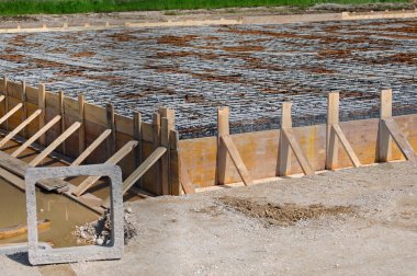 square concrete product and formwork made with yellow planks during laying cement to make the foundation of the building clipart