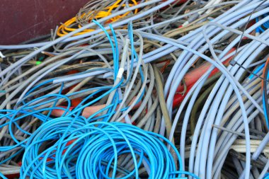 Geri dönüşüm merkezinde atık toplama ve malzeme geri dönüşümü için eski bakır ve PVC elektrik kabloları bulunan bir konteynırın içinde.