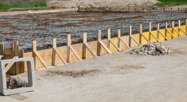 formwork made with yellow planks during laying cement to make the foundation of the building on the construction site without people clipart