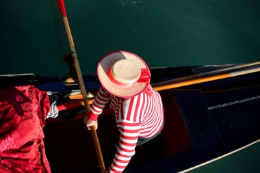 gondolier in Venice Italy  with typical Venetian clothes and large straw hat while rowing on the gondola on the Grand Canal clipart