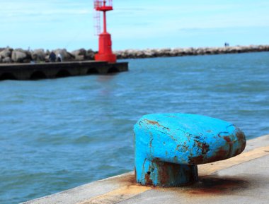 large blue bollard that serves to securely moor ships to the port and a red lighthouse in the background clipart
