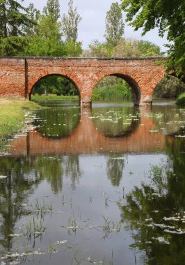 Üç Kollu Kırmızı Tuğla Köprüsü 'nün Akan Nehir üzerindeki yansıması