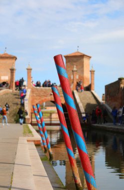 mooring poles for boats in the navigable canal and the ancient bridge of COMACCHIO in Central Italy clipart