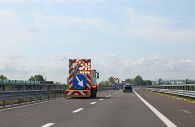 Yol bakım kamyonu üzerinde kocaman bir tabela ve şeridi daraltmak için çok büyük bir ok var.
