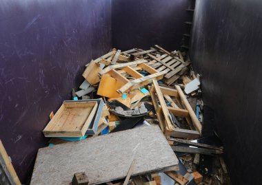 Eski ahşap kalaslar ve geri dönüşüm için kırık mobilyalarla dolu büyük bir kap.