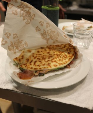 Tipik İtalyan yemeği, restoranda çiğ jambon ve yeşil roketle bir tabakta pişmiş doldurulmuş Piadina 'dır.