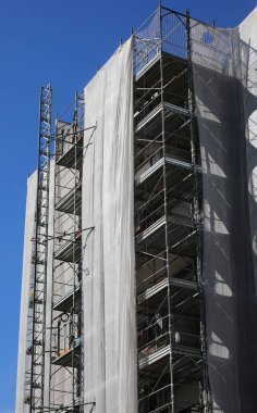 Enerji tüketimini azaltmak için izolasyon panellerinin montajı sırasında birçok dairesi olan yüksek katlı bir binanın inşaat iskelesi para tasarrufu için
