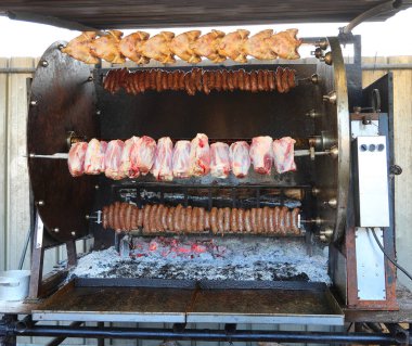 Bir açık hava restoranının açık ateşinde pişen şiş üzerinde domuz eti ve sosis ile endüstriyel rosto.