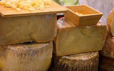 Peynir tezgahında taze ve olgun peynirler satılıyor. Tekerlekler, dilimler ve tadımlık tabaklar.