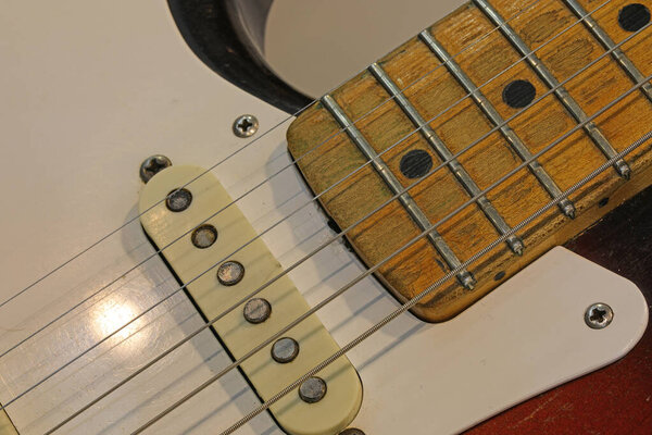 Heavily worn and played vintage electric guitar with detail of the worn wooden neck and pickups