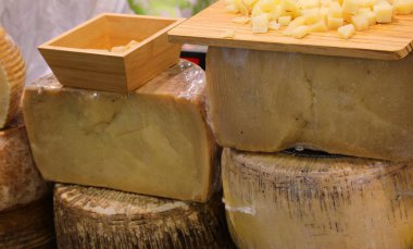 Peynir tezgahında taze ve olgun peynirler satılıyor. Tekerlekler, dilimler ve tadımlık tabaklar.