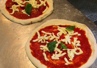 Pişmemiş pizza İtalyan pizzacıda domates sosu mozzarella ve yeşil fesleğenle hazırlandı.