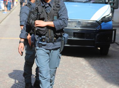Şehirde bir protesto gösterisi ve zırhlı polis minibüsü sırasında kurşun geçirmez yelek giymiş bir polis memuru.