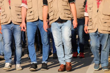 Bir grup kahverengi yelekli işçi grev sırasında yürüyorlar ve şehirdeki protesto gösterisine katılıyorlar.