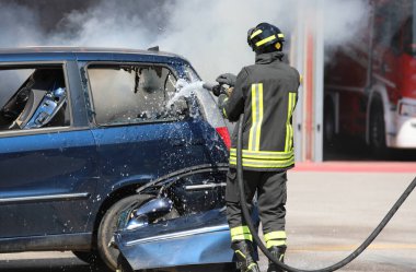 Şehirdeki isyancıların ayaklanması sırasında yanan arabadaki yangını itfaiyeciler söndürdü.