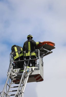 Kurtarma sırasında iki itfaiyeci havada asılı sedye ile vinçte.