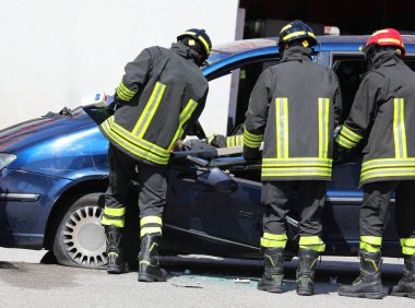 Koruyucu ekipmanlı itfaiyeciler trafik kazasından sonra yaralıyı arabadan çıkardılar.
