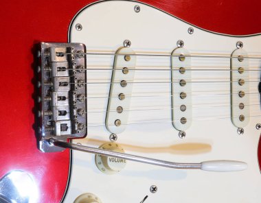Ses düğmeleri ve titrek kollu kırmızı beyaz bir elektro gitarın yakın çekimi.