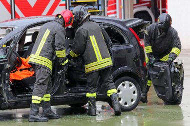 Üniformalı itfaiyeciler çarpışmadan sonra çarpan bir arabanın kapısını açarak yaralı kişiyi metal levha tezgahından kurtardılar.