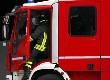 İtfaiyeci acil durum sırasında hızla kırmızı itfaiye aracından iniyor.
