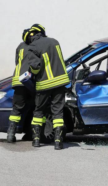stock image Firefighters using a hydraulic rescue tool called Jaws of Life to pry open the door of a crashed car
