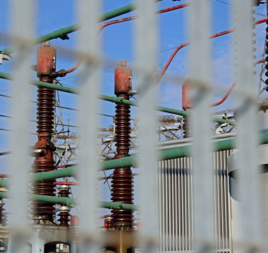 Çitin dışından görülen hidroelektrik santralinde yüksek voltajlı endüstriyel şalterler.