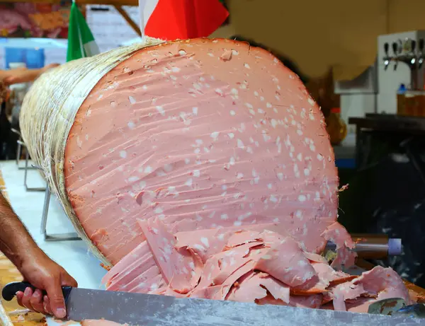 stock image Italian salami called  mortadella GIGANTE sliced with a long knife during the town festival