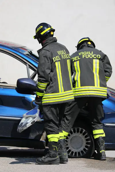 stock image Vicenza, VI, Italy - May 23, 2024: Two Italian firefighters using the Jaws of Life to pry open the door of a wrecked car