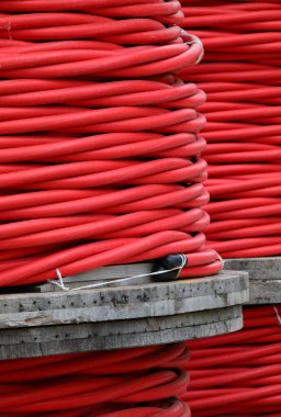 many coils Insulated high voltage red electric cable in the warehouse of the power company before laying clipart