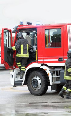İtfaiyeci acil bir durum sırasında itfaiye aracından hızla indi.