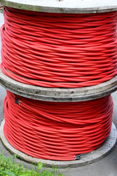 Elektrik şirketinin deposunda yüksek voltajlı yalıtılmış kırmızı elektrik kablosu makaraları var.