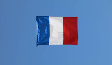 Mavi gökyüzünde asılı duran büyük Fransız bayrağı görünüşte desteksiz.
