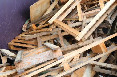 Uygun atık imhası için çöp sahasındaki ahşap geri dönüşüm konteynerinde kullanılmış ahşap tahtalar ve kırık paletler.