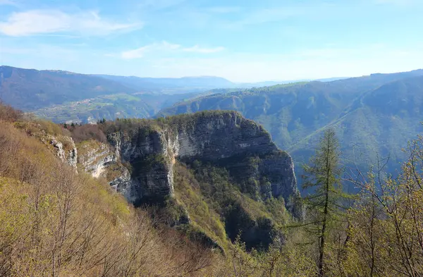 stock image Steep overhanging rock face and the Italian Alps seen from a mountain peak