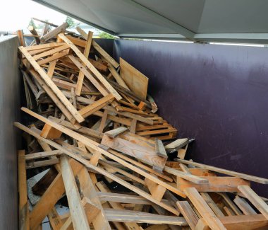 Ahşap kalaslar ve kırık paletler çöplükteki geri dönüşüm konteynerinde uygun atık depolama için.