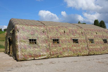 camouflaged military tent set up in a training camp during wartime with no people clipart