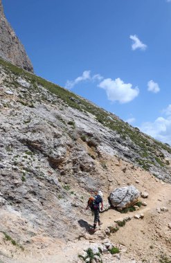 Sırt çantalı bir yürüyüşçü İtalya 'nın kuzeyindeki Dolomitler Alplerinde bir patika boyunca yürüyor.