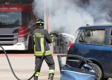 Vicenza, VI, İtalya - 23 Mayıs 2024: İtalyan itfaiyeci kaza yapan araba yangınını söndürmek için hortumdan su ve söndürücü sıktı