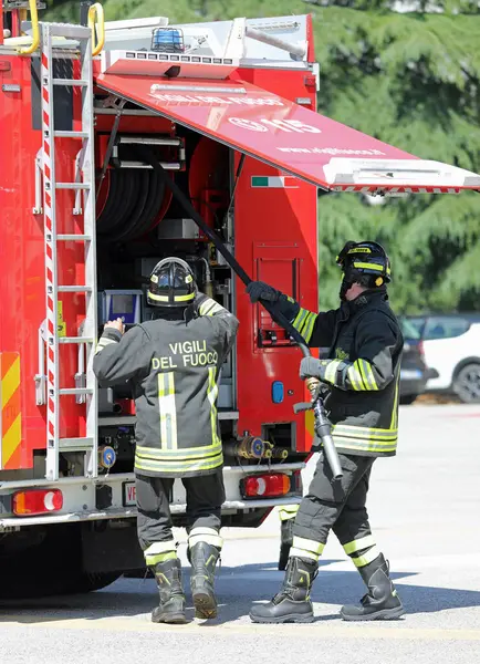 Vicenza, VI, İtalya - 23 Mayıs 2024: İtalyan itfaiyeciler acil durum sırasında itfaiye aracına bağlı hortum hortumunu alın