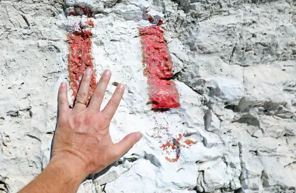 stock image hand of man with the ring and the colored symbol of the path to follow painted on the rock