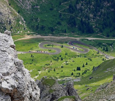 Kuzey İtalya 'da yaz mevsiminde Dolomite geçidine ulaşmak için virajlı virajlı yollar ve dağ yamaçlarına tırmanan bazı arabalar.