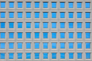 Modern bir gökdelenin mavi camlı birçok penceresi var.