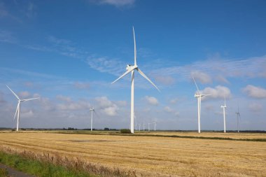 wind turbines on the plain in the middle of the cultivated field for the production of electricity from renewable sources without CO2 emissions clipart